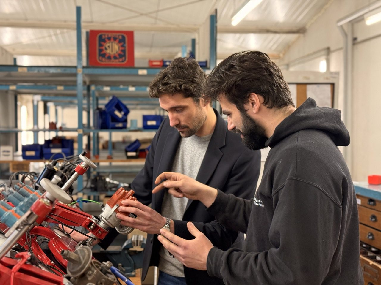 Radspieler Ignition workshop — two technicians inspecting Bosch ignition distributor at test bench, Germany